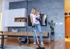 woman using a vacuum with baby